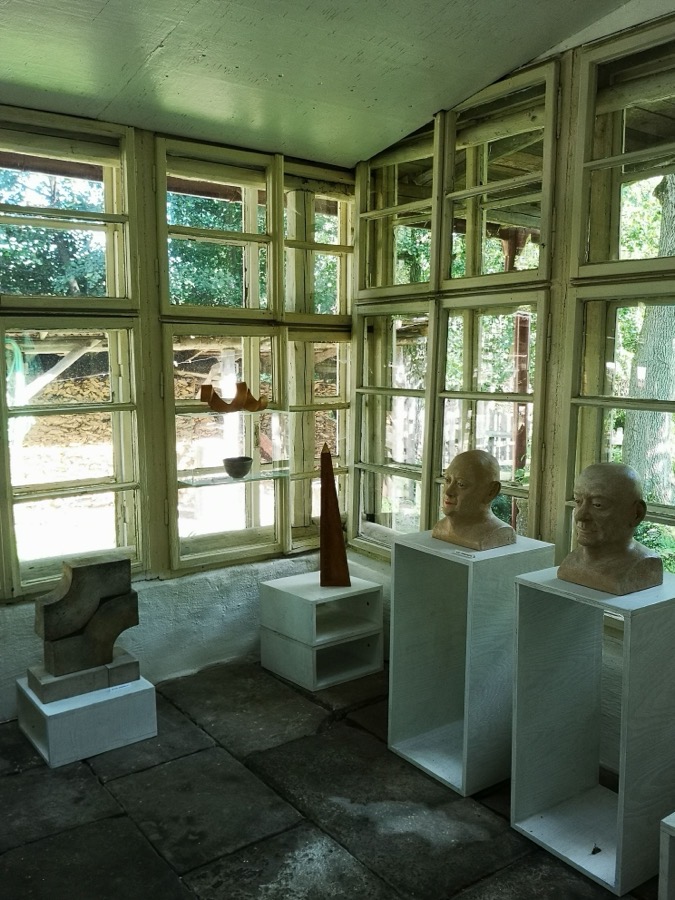 Prosklená galerie školy, na bílých soklech keramické busty a plastiky